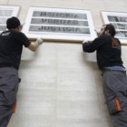 Dos operarios colocan una de las obras de la exposición 'Desaparecidos' de Gervasio Sánchez