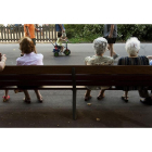 Un grupo de ancianos descansan en un banco en un parque de Barcelona. /