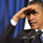 Obama se cubre los ojos para evitar el reflejo de los focos mientras escucha una pregunta.