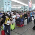 Pasajeros hacen cola para facturar las maletas que no pueden embarcar como equipaje de mano, en el aeropuerto de El Prat.
