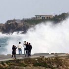 Varias personas miran las olas en la playa de Riazor de A Coruña.