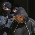 Un agente de los mossos traslada a uno de los detenidos en la operación policial de ayer.
