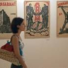 Una visitante pasa junto a tres carteles de la exposición