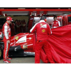 Alonso mira cómo los mecánicos destapan su Ferrari, en Montmeló.