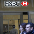 Varias personas pasan por delante de una sucursal del banco HSBC.