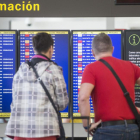 Dos viajeros observan el panel de salidas en el aeropuerto de El Prat, en plena huelga de controladores en Francia.