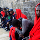 Algunos de las personas de origen subsahariano rescatadas por Salvamento y atendidas por Cruz Roja esperan en el puerto de Tarifa su traslado por la Guardia Civil.