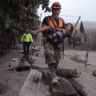 Un trabajador de los equipos de rescate de Guatemala ayuda a una niña en la zona de El Rodeo. NOÉ PÉREZ