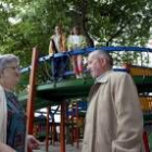 Dos abuelos que se encuentran haciendo de canguros de sus nietos en uno de los parques españoles