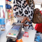 Una consumidora paga con trjeta en una tienda de ropa.