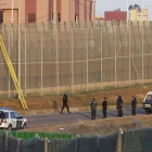Varios subsaharianos encaramados en la valla de Melilla, este martes.