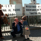 Un padre bromea con su pequeña hija junto a unas pancartas de la Asociación de Padres de Familia Separados.