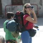 Una peregrina con la mochila a la espalda, sacando una fotografía durante su estancia en Ponferrada