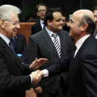 Mario Monti y Luis de Guindos se saludan este lunes en Bruselas.