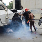 Un manifestante yace bajo una tanqueta policial en Caracas.