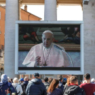 Turistas y los fieles católicos con máscaras médicas observan una pantalla gigante instalada en la Plaza de San Pedro. RICCARDO ANTIMIANI