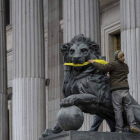 Una activista de Greenpeace amordaza los leones del Congreso de los Diputados.