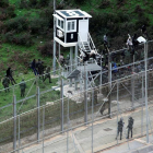 Varios inmigrantes custodiados por la policia marroquí junto a la valla de Ceuta.