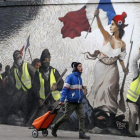 Un hombre pasa junto a un mural que reproduce una versión de La libertad guiando al pueblo, de  Eugene Delacroix, con la presencia de chalecos amarillos, idea del artista Pascal Boyart.