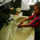 Un pequeño se quita el reloj antes de lavarse las manos en el cuarto de baño de su casa