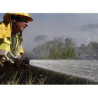 Un miembro de una brigada contra incendios apaga el fuego en un monte de León