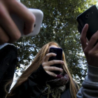 Unos adolescentes utilizan su teléfono móvil.
