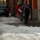 Dos vecinos de San Andrés retiran el hielo y la nieve de las aceras.