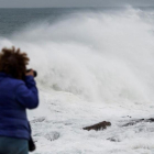 Una mujer fotografía el fuerte oleaje del mar Cantábrico en el pueblo de Rinlo, en Ribadeo (Lugo). /