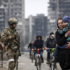 Una mujer pasa con su hijo ante militares rusos en Mariúpol, ayer. SERGEI ILNITSKY