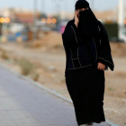 Una mujer saudi habla por teléfono mientras camina por una calle de Riad