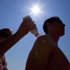 Unos turistas italianos se aplican protección solar en la playa de la Barceloneta.