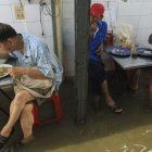 Clientes comen con el agua por los tobillos en un restaurante inundado situado en el mercado Tha Phrachan, en Bangkok (Tailandia), hoy.