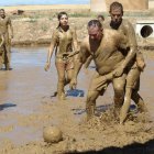 Los entregados deportistas se disputan el balón en un peculiar campo de fútbol-barro.