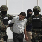 Joaquin 'El Chapo' Guzman es escoltado por dos soldados mexicanos tras su detención.