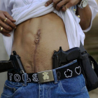 Un traficante de drogas muestra su herida de bala y su arma en Caracas.
