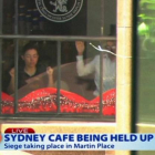 Dos de los rehenes, contra las ventanas del café Lindt Chocolate Cafe, del centro de Sídney, este lunes.