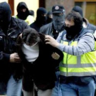 Policías conducen en Bilbao a uno de los cinco miembros de una banda de atracadores.