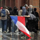 Un manifestante porta una bandera chilena mientras se enfrenta a la policía.
