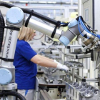 Un brazo robotizado, junto a una trabajadora, en la fábrica de Volkswagen en Salzgitter (Alemania).