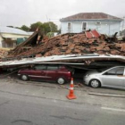 Unos coches se encuentran debajo de un edificio destruido por el terremoto.