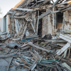 Un hombre recoge restos de madera junto a su casa destruida por los combates.