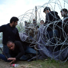Refugiados sirios cruzan la alambrada de espino situada por las autoridades húngaras en su frontera.