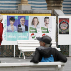 Unos ciudadanos observan carteles electorales ayer en San Sebastián, tras el anuncio de renuncia de los siete exetarras. JUAN HERRERO