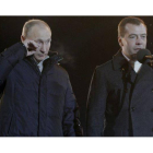 Vladimir Putin, junto al presidente Dmitri Medvedev, se seca las lágrimas, durante un acto con sus seguidores a las puertas del Kremlin, el domingo, tras las elecciones. Ivan Sekretarev | AP