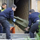 Operarios de la funeraria retiran el cuerpo de la mujer asesinada.