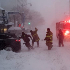 Un bombero ayuda a empujar un camión atrapado en la nieve.