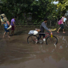 Varias personas caminan con frazadas y provision por una calle inundada despues que un cauce se desbordara  en el municipio de Tipitapa.