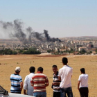 Gente mira el humo de los combates en Kobane desde la frontera turca.