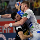 El lateral español Alex Dujshebaev choca contra el pivote esloveno Blagotinsek