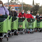 Ciudadanos ataviados con guantes y mascarillas hacen cola para comprar en Roma.